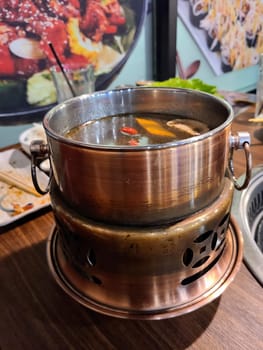 Steaming hot pot with mushrooms and goji berries in a cozy restaurant setting, showcasing communal dining in Fort Wayne, Indiana.