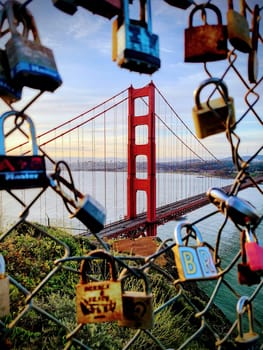 Golden Gate Bridge viewed through a vibrant array of love locks in San Francisco, California, symbolizing romance and timeless commitment, 2022