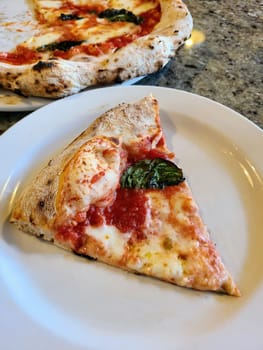 Authentic Margherita pizza slice on ceramic plate in a cozy Indiana restaurant, 2023