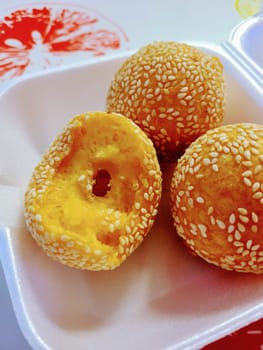 Close-up of crispy sesame seed balls, a traditional Asian dessert, served on a takeaway tray in a casual setting in Louisville, Kentucky, 2023