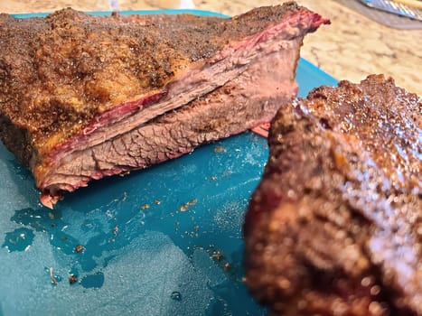 Juicy smoked beef brisket on blue cutting board in cozy kitchen setting, Fort Wayne, Indiana, 2023