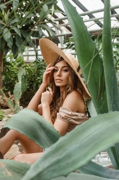 A beautiful young woman takes care of plants in a greenhouse. The concept of gardening and an eco-friendly lifestyle