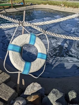 Lifebuoy on wooden post at a sunny outdoor pool in Muncie, Indiana, highlighting water safety and leisure