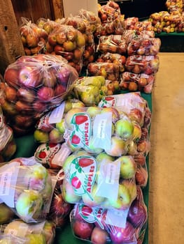 Freshly harvested, multi-colored apples from Fort Wayne, Indiana orchard on display in clear labeled bags at an indoor market