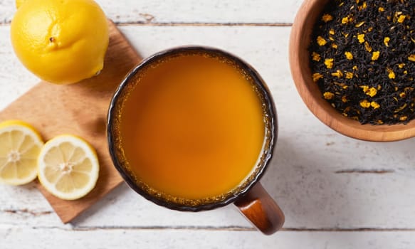 Top view of cup with black tea, turmeric, honey and lemon on white background.