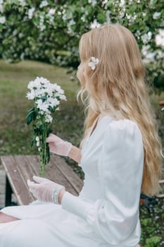 A blonde girl with long hair on a walk in a spring park. Springtime and blooming apple trees