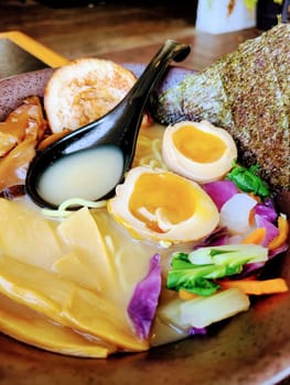 Vibrant bowl of gourmet ramen with soft-boiled egg, chashu pork, and fresh vegetables, beautifully arranged in a Japanese restaurant, Warsaw 2023