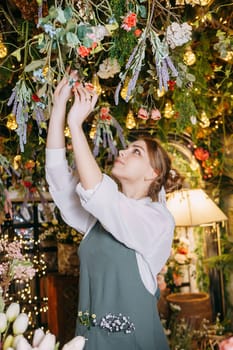 A woman in her florist shop collects bouquets of flowers. The concept of a small business. Bouquets of tulips for the holiday on March 8