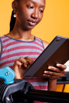 Dedicated black woman searching on internet using phone tablet to research on bike maintenance. Close-up of healthy active female cyclist grasping smart device with instructions for fixing bicycle.