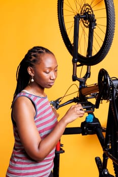 Sporty african american female cyclist repairing and maintaining to ensure top-notch performance. Detailed view of healthy black woman meticulously examining and correcting bicycle pedal.