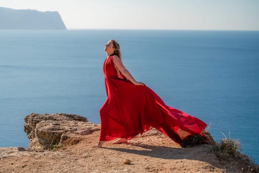 A woman in a red flying dress fluttering in the wind, against the backdrop of the sea