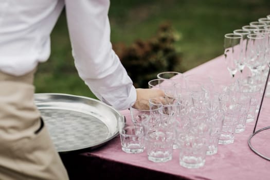 waiter removes empty glasses after a party or wedding