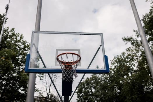 basketball hoop with a net on the background of trees in the park.