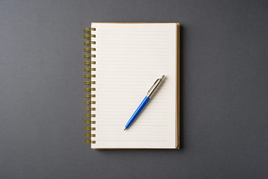 Ballpoint pen made of blue plastic and metal standing on lined notebook