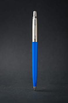 Blue plastic and metal ballpoint pen on dark gray background