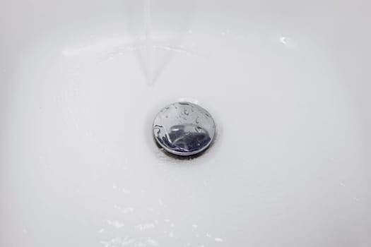 Water flowing down the drain in the washbasin