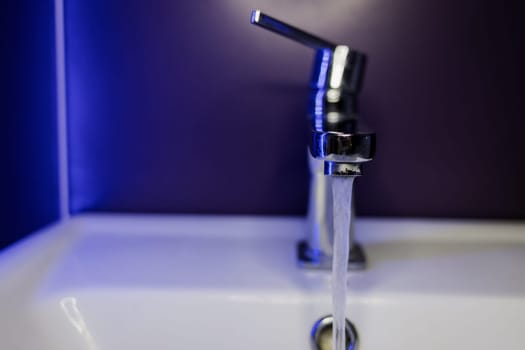 Faucet with flowing water closeup. Silver chrome water faucet 