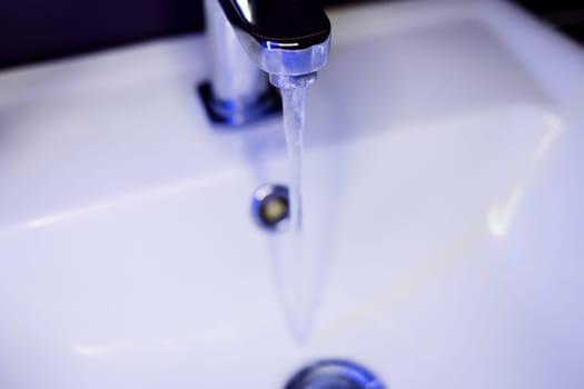 Flowing water from tap on blue background