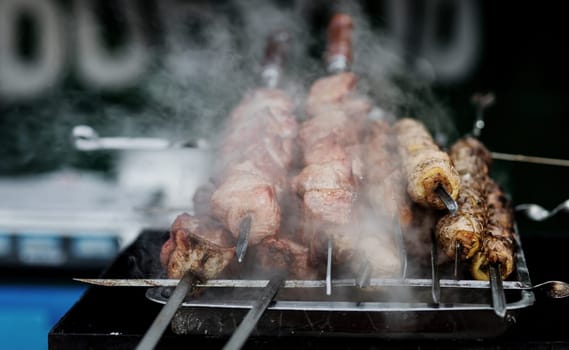 Shashlik or shish kebab prepared on barbecue grill over hot charcoal. Grilled pieces of pork meat on metal skewers.