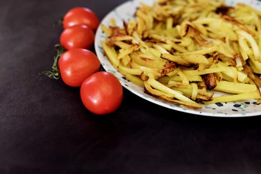 closeup view of a plate of fry potatoes and red tomatoes in a restaurant