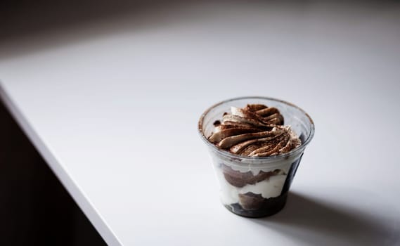 Sweet dessert with chocolate and white airy cream in a transparent glass. 