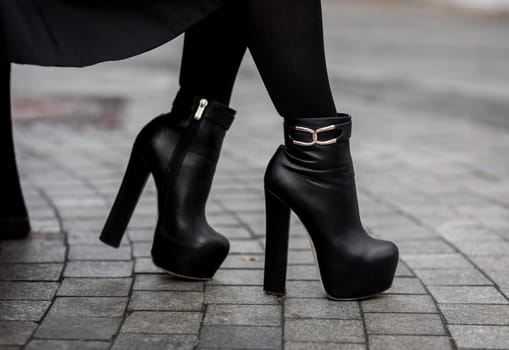 Elegant outfit. Closeup of stylish black ankle boots. Fashionable girl on the street. City lifestyle. Female fashion