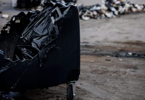 Melted trash bin in street. Unknown pests burned a plastic trash can.