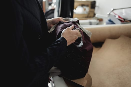 the tailor is holding a cloth in his hands. fashion designer