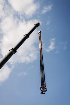 crane boom with hooks on blue sky background