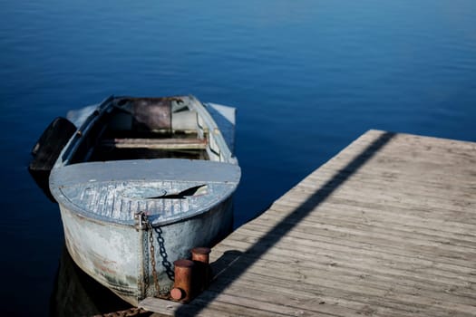 Old small boat floating on the lake near the pier.