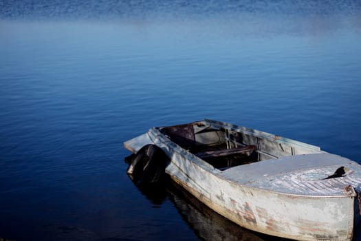 Lonely row boat at lake with blue water. Copy space