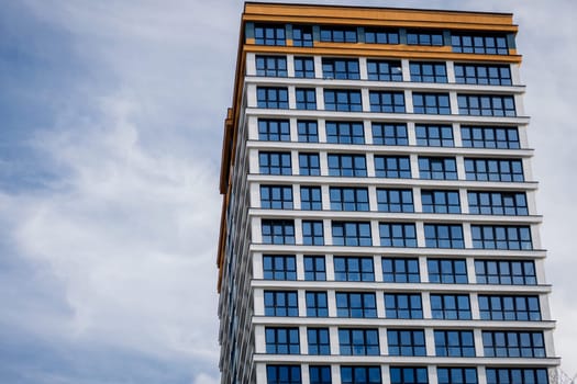 a blue facade with many windows of a residential building against the sky. copy space