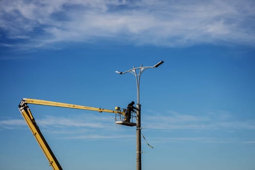 Street light repair works, worker repair street lamp at height, led lights replacement. 