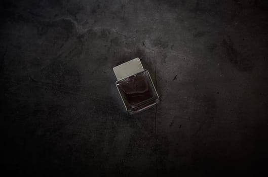 transparent fragrance perfume bottle on dark empty background. Top view. Horizontal. men's  cologne