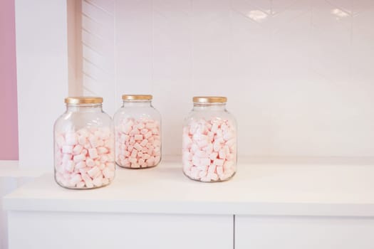 Three glass jars to marshmallow on table of kitchen. selective focus