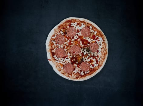 Raw Pizza on dark background. Original italian pepperoni pizza