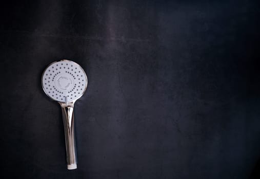 stainless steel shower head with the turn lever of a spray settings on a dark background. copy space