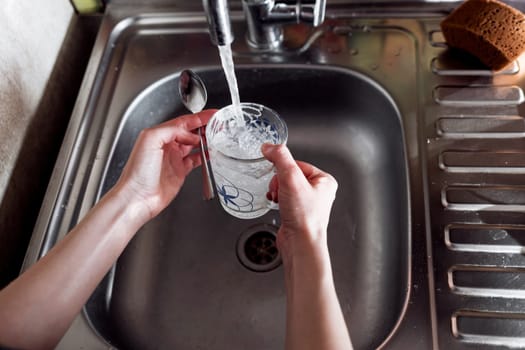 Human hand washing dish or pouring glass with fresh drink water at kitchen fauce