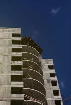 unfinished high-rise building on a construction site. The new building is being built against a blue sky. Mortgage