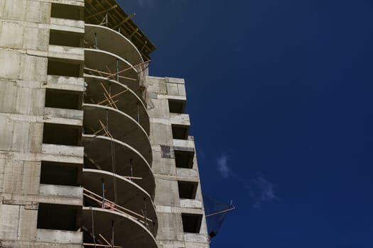 Unfinished cement building on a construction site. The new building is being built against the blue sky