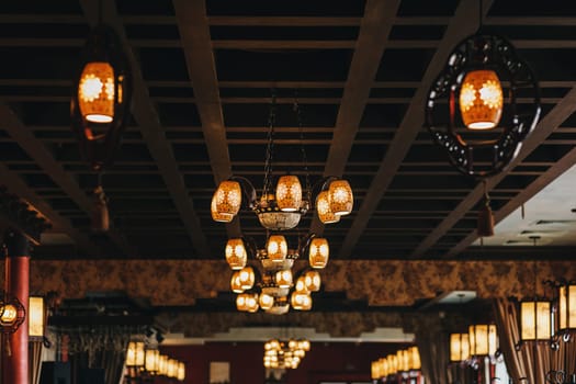 Warm lighting coming out from beautiful lamps on ceiling. Trendy cafe with nice environment