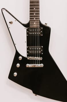 An electric guitar hangs on a white wall in the studio