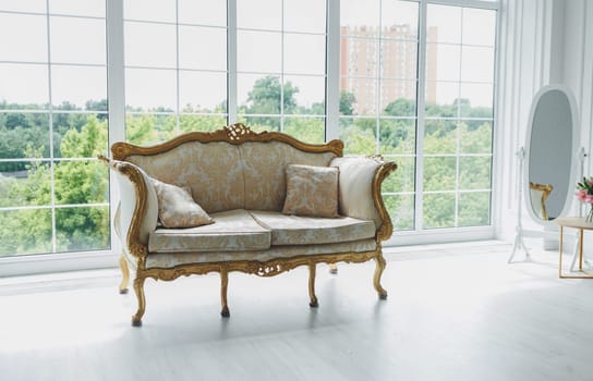 Vintage royal sofa in a room near big window. Classic interior