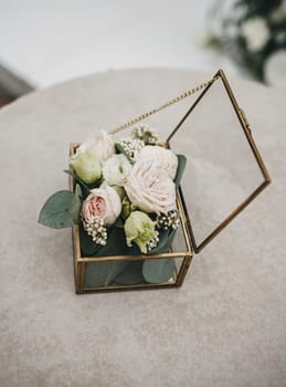 Glass box for wedding rings decorated with fresh rose flowers. Event decoration with fresh flowers.