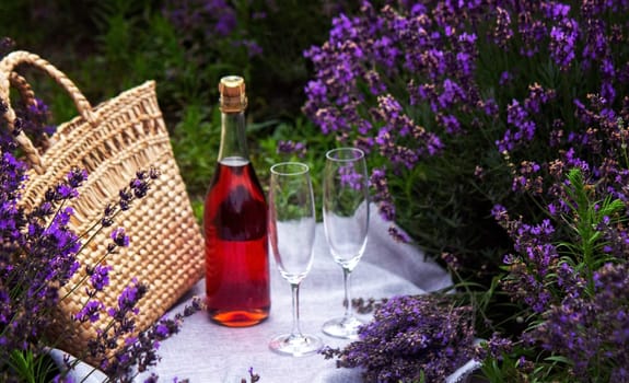 two glasses and pink wine in a lavender field. Violet flowers on the background.