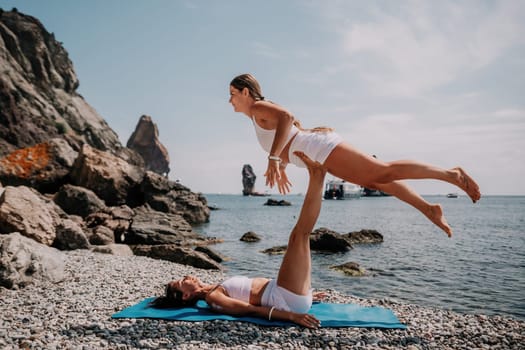 Woman sea yoga. Back view of free calm happy satisfied woman with long hair standing on top rock with yoga position against of sky by the sea. Healthy lifestyle outdoors in nature, fitness concept.