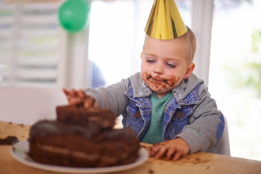 Baby, birthday and eating cake in home, celebration for infant or party. Happy boy, dessert on table or excited cheerful event for growth with special decoration hat or messy face and childhood fun.