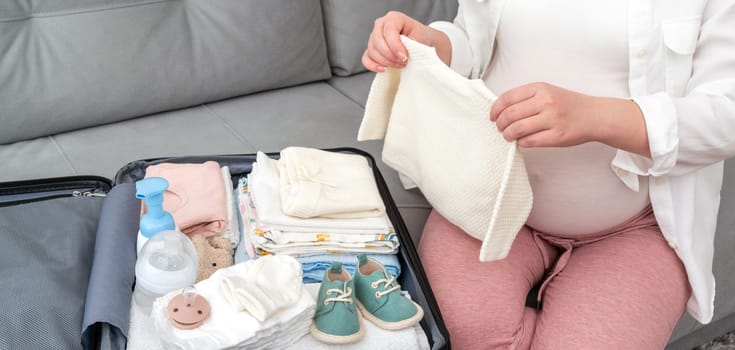 Pregnant woman packing things in a suitcase.