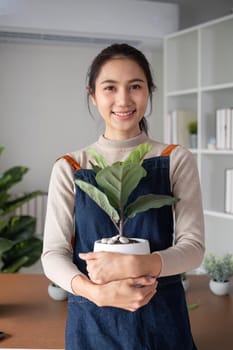 A young Asian woman is enjoying planting a garden in her home to create a shady atmosphere in her home..