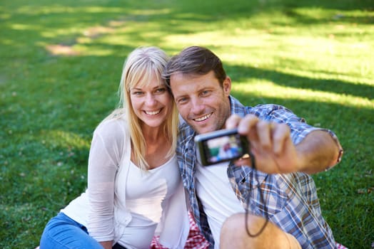 Selfie, camera and couple in a park, love and happiness with marriage and romance with summer or nature. Photograph, outdoor or memory with man or woman with relationship, relax or date with sunshine.